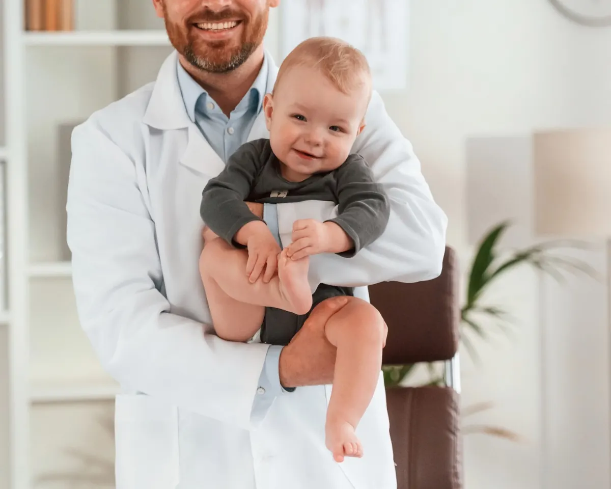 Pediatra segurando um bebê sorridente